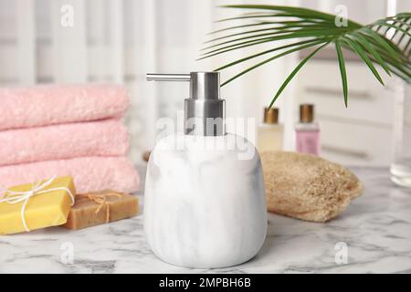 Dispenser per marmo, saponette e spugna luffa sul tavolo Foto Stock