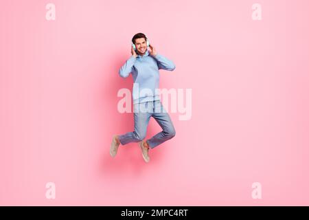 Foto di positivo overjoyed uomo indossare abiti blu trendy godere di successi moderni preferiti ucraino musica band isolato su sfondo di colore rosa Foto Stock