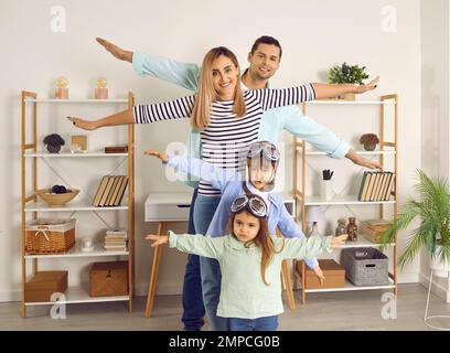 Bambini felici insieme con loro mamma e papà che giocano piloti e aerei a casa Foto Stock