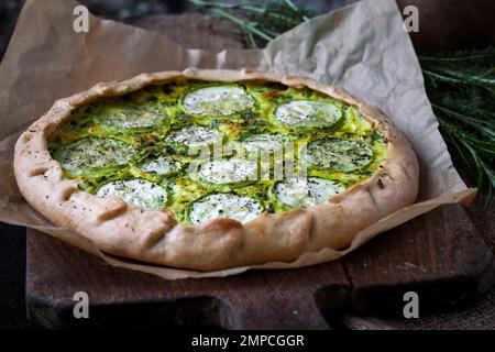 Zucchine fatte in casa e torta di formaggio di capra su uno sfondo rustico scuro in legno. Cibo in stile rustico Foto Stock