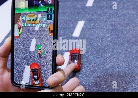 Norimberga, Germania. 31st Jan, 2023. Tramite uno smartphone, che cattura una vera e propria auto giocattolo con la fotocamera, una scena stradale virtuale viene visualizzata durante lo spettacolo di novità alla Spielwarenmesse nel gioco Zombie Crasher AR di Augmented Robotics. Tramite app, che collega il mondo reale al mondo digitale con l'intelligenza artificiale, l'auto reale viene quindi utilizzata per colpire gli zombie nel gioco. Il 72nd Spielwarenmesse si svolge dal 1 al 5 febbraio 2023. Credit: Daniel Karmann/dpa/Alamy Live News Foto Stock