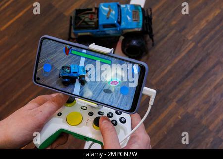 Norimberga, Germania. 31st Jan, 2023. Utilizzando uno smartphone che cattura una vera auto telecomandata con una telecamera, il veicolo viene guidato verso un oggetto virtuale durante il gioco RoboHeart AR Racer di Augmented Robotics al Toy Fair's Innovation Show. Tramite app, che collega il mondo reale con il mondo digitale utilizzando l'intelligenza artificiale, l'auto reale viene quindi utilizzata per raccogliere oggetti nel gioco. Il 72nd Spielwarenmesse si terrà dal 1 al 5 febbraio 2023. Credit: Daniel Karmann/dpa/Alamy Live News Foto Stock
