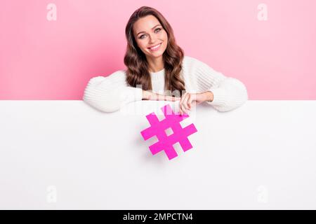 Foto di allegro bella donna mano tenere carta hashtag simbolo vuoto spazio vuoto isolato su sfondo di colore rosa Foto Stock