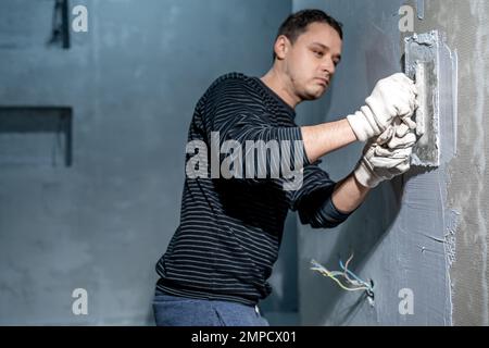 l'uomo applica l'isolamento alla parete di un bagno Foto Stock