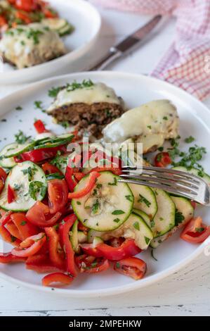 Cena o pranzo a basso contenuto di carboidrati con insalata mediterranea fresca e polpette o hamburger su piatto Foto Stock