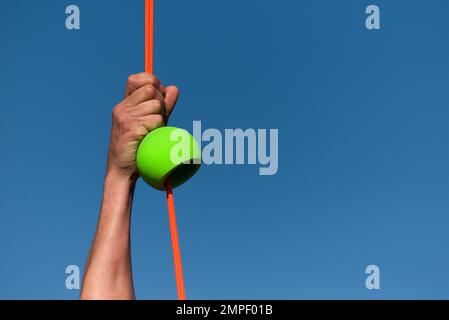 Uomo atletico che lavora fuori e arrampicandosi su una corda durante il corso di ostacolo nel campo di stivale, raggiungendo la meta Foto Stock