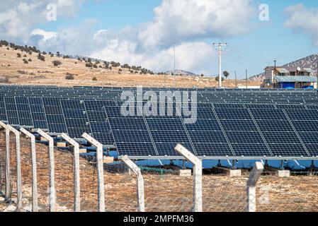 Campo solare con pannelli solari recintati al tramonto Foto Stock