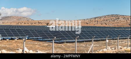 Campo solare con pannelli solari recintati al tramonto Foto Stock