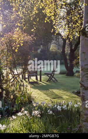 Mobili in legno soleggiato circondati da fiori e alberi nel giardino di Natalie Finch, aprile 2005 Foto Stock