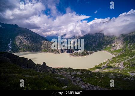 Vista dal Passo Grimsel sul lago artificiale Grimselsee e sull'Alpinhotel Grimsel Hospiz, le montagne circostanti sono circondate da nuvole. Foto Stock
