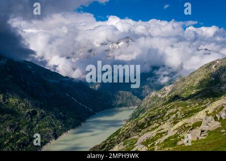 Vista sul lago artificiale Grimselsee, le cime delle montagne opposte Galenstock e Dammastock sono avvolte da nuvole. Foto Stock