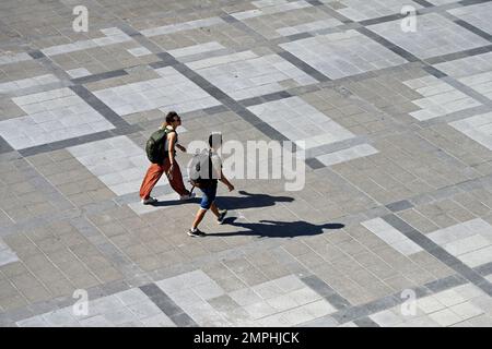 Vista dall'alto di due persone che camminano nella piazza pubblica con ombre Foto Stock
