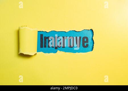 Migliorare la scrittura con lettere di timbro sulla grana della carta blu attraverso una striscia strappata su carta gialla. Foto Stock