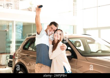 Coppia felice con la chiave dell'automobile nella concessionaria auto moderna Foto Stock