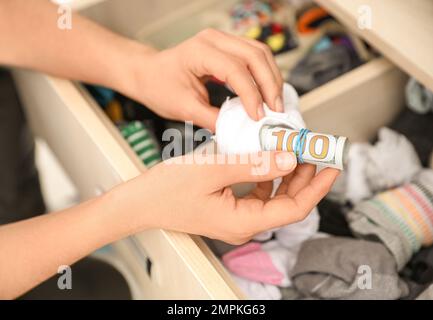 Donna che nasconde denaro in calzino, primo piano. Risparmi finanziari Foto Stock