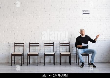 sceneggiatura di lettura dell'attore di mezza età barbuto in attesa di lancio in sala Foto Stock