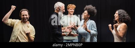 produttore tatuato che parla con felice afroamericana vicino entusiasti attori multietnici, banner. Traduzione del tatuaggio: kanji, pericolo Foto Stock
