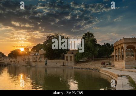 Tramonto spettacolare sul lago Gadisar, Jaisalmer, Rajasthan, India. Tramontare il sole e le nuvole colorate nel cielo con vista sul lago Gadisar. Un luogo turistico. Foto Stock