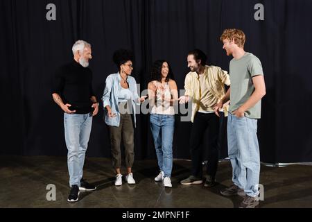 allievo allegro che parla e gesturing vicino al direttore d'arte nella scuola del teatro Foto Stock