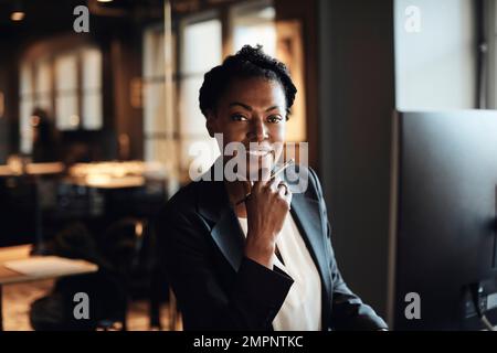 Donna d'affari matura sorridente con mano sul mento in ufficio Foto Stock