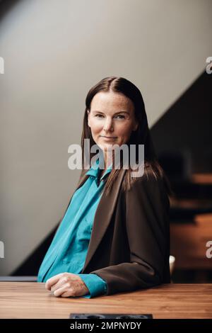 Ritratto di donna d'affari incinta sicura seduta alla scrivania in ufficio Foto Stock