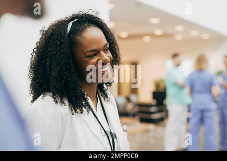 Felice medico femminile con capelli ricci in ospedale Foto Stock