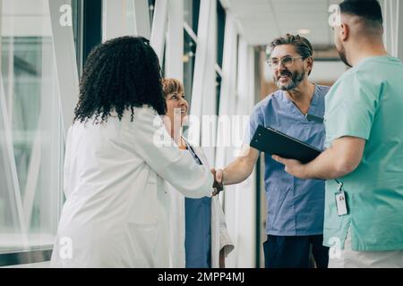 Medico maschile che fa stretta di mano con una collega all'ospedale Foto Stock