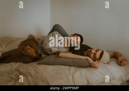 L'uomo si rilassa con il ragazzo mentre si sdraiava a letto a casa Foto Stock