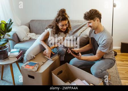Uomo che condivide la cornice fotografica con la ragazza mentre disimballa scatole di cartone a casa Foto Stock