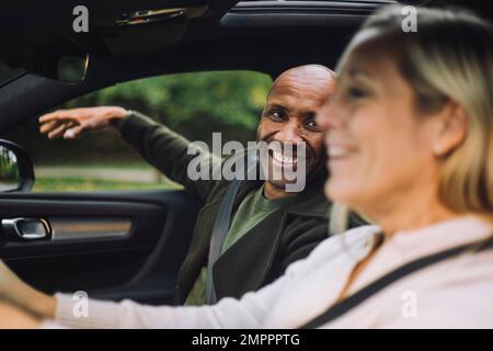 Felice uomo calvo guardando la donna alla guida di auto Foto Stock