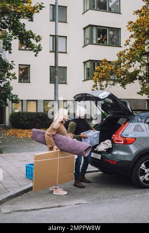 Coppia matura che carica i bagagli nel bagagliaio dell'auto durante il trasferimento della casa Foto Stock
