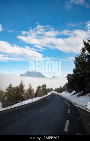 Strada in inverno con neve e nebbia nella valle, Alpi francesi, Francia Foto Stock