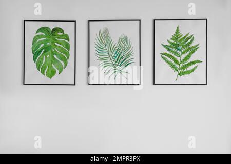 Splendidi dipinti di foglie tropicali appesi su pareti bianche Foto Stock
