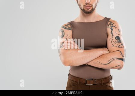 Vista ritagliata dell'uomo tatuato barbuto che attraversa le braccia isolate sul grigio Foto Stock
