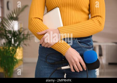 Giornalista professionista con moderno microfono e notebook in camera, guardaroba Foto Stock