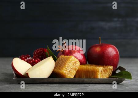 Favi, mele e melograno su tavola grigia. Rosh Hashanah vacanza Foto Stock