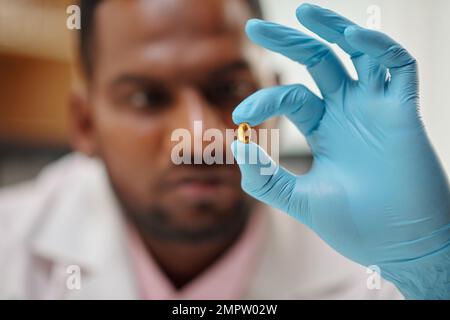 Medico scienziato che tiene la pillola con olio di pesce, fuoco selettivo Foto Stock