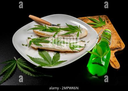 Piatto bianco con ciambelle di burro decorato verde marijuana Matanuska foglie varietà su tavola nera Foto Stock