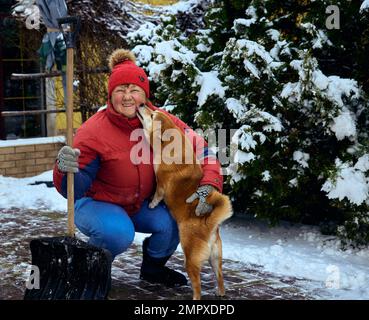 Donna matura carina in giacca rossa con cane di razza shiba inu Foto Stock