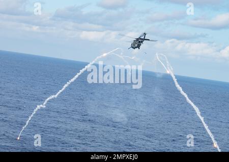 Un falco di nave HH-60 del 33rd Rescue Squadron spara razzi mentre conduce manovre evasive in un'area di addestramento designata sopra l'Oceano Pacifico, 22 novembre 2022. Il 33rd RQS si adopera per la mobilitazione, lo spiegamento e l'impiego di elicotteri e per il salvataggio di militari statunitensi e alleati e di personale civile. Foto Stock