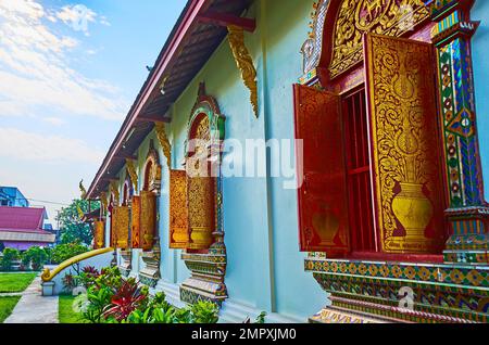 Persiane in legno e cornici ornate della finestra del viharn nel tempio Wat Chiang Man, Chiang mai, Thailandia Foto Stock