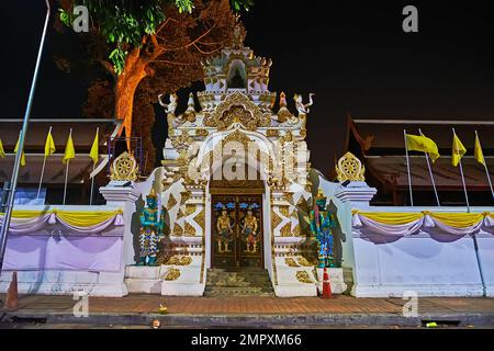 La porta riccamente decorata di Wat Chedi Luang con sculture di divinità Devata, serpenti Naga e guardiani Yaksha contro il cielo scuro della sera, Chian Foto Stock