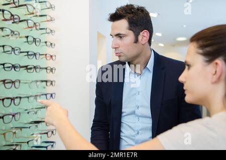 All'ottico optometrista femmina ad aiutare il paziente a scegliere nuovi occhiali Foto Stock