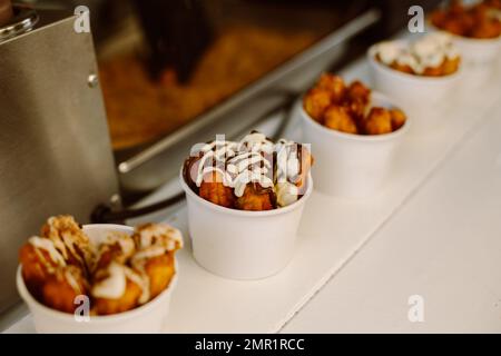 Deliziosi bastoncini di churros con crema e cioccolato in un bar di strada. Cibo spagnolo dolce di strada. Foto Stock