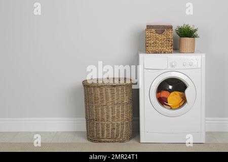 Cestini in vimini con lavanderia e lavatrice vicino alla parete rosa Foto  stock - Alamy