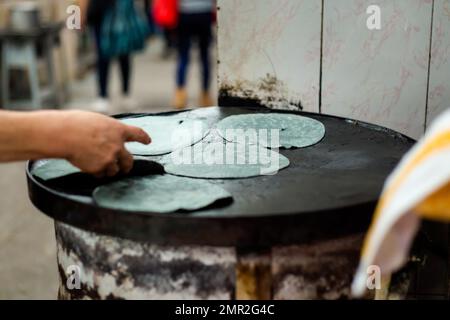 Preparazione di tortillas di mais fresco blu sul mercato locale a Puebla. Cucina messicana tradizionale a base di ingredienti freschi. Foto Stock