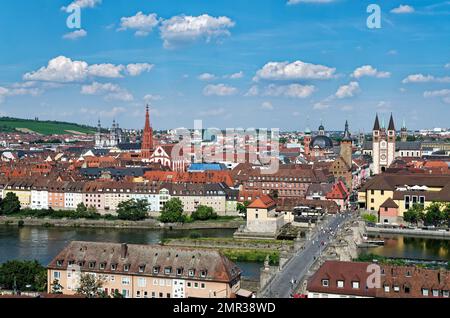 Würzburg vista panoramica sul vecchio ponte principale sotto il cielo blu in una giornata di sole con alcune nuvole e il fiume meno in primo piano Foto Stock