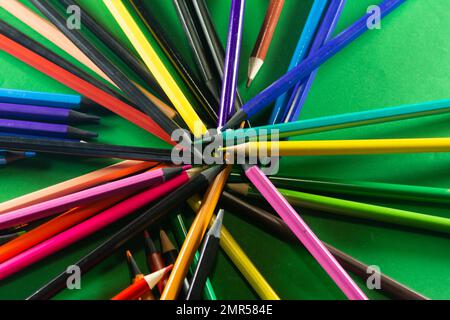 Diversi pastelli sparsi intorno. Isolato su sfondo verde. Primo piano. Foto Stock