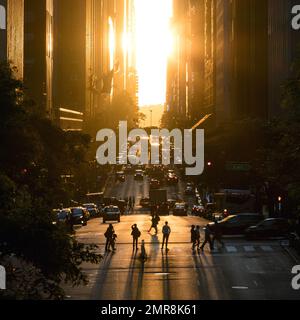 Persone, auto, autobus e taxi affollato insieme sulla 42nd Street a Manhattan New York City con la luce del tramonto che splende tra la costruzione sfondo Foto Stock