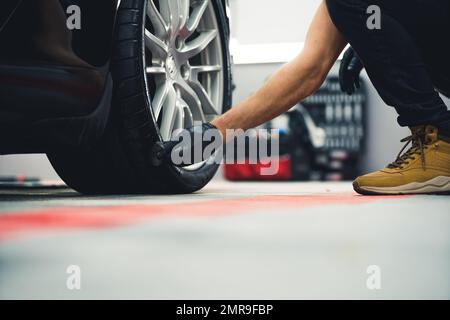 Annerimento degli pneumatici. Uomo irriconoscibile con guanti neri che annerisce le gomme dell'automobile usando la spugna. Prospettiva ad angolo basso. Foto di alta qualità Foto Stock